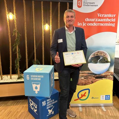 Stefaan Lemey poseert met de SDG PIONEER Award in het park.